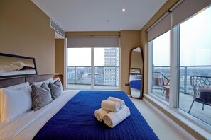 Een hotelkamer met een groot bed, een balkon met uitzicht op de stad en een grote spiegel.