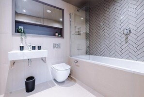 Un bagno moderno con lavandino, water e vasca da bagno bianchi.