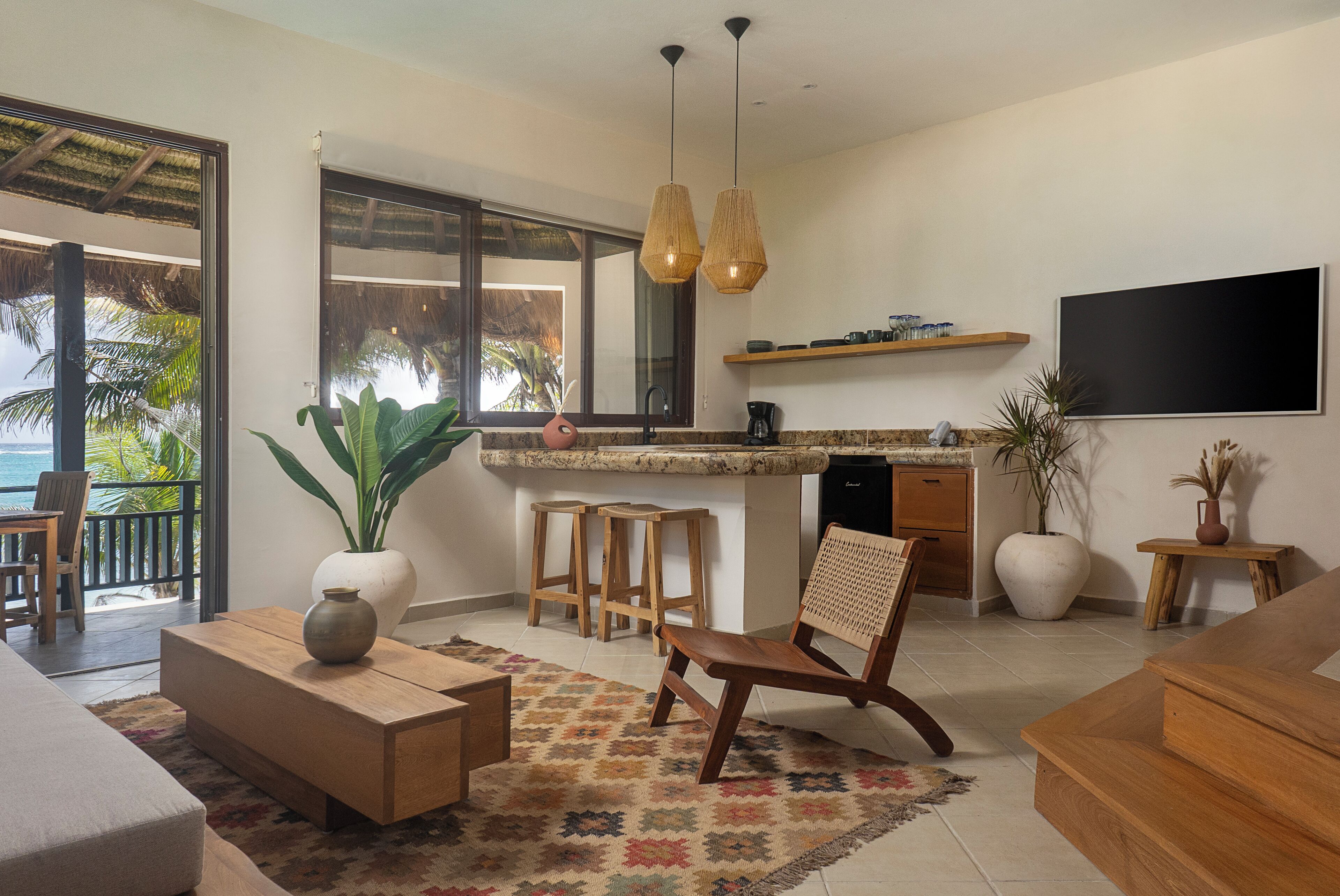 A modern kitchen with a large island, bar stools, and a dining area with a wooden table and chairs.