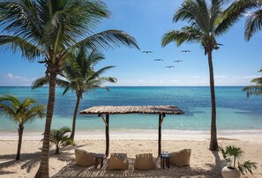 Een privéstrand, ligstoelen aan het strand, parasols, strandlakens