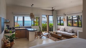 A modern, open-plan living space with a kitchen, dining area, and seating by a large window overlooking the ocean. - Mantaray Tulum (Tulum)