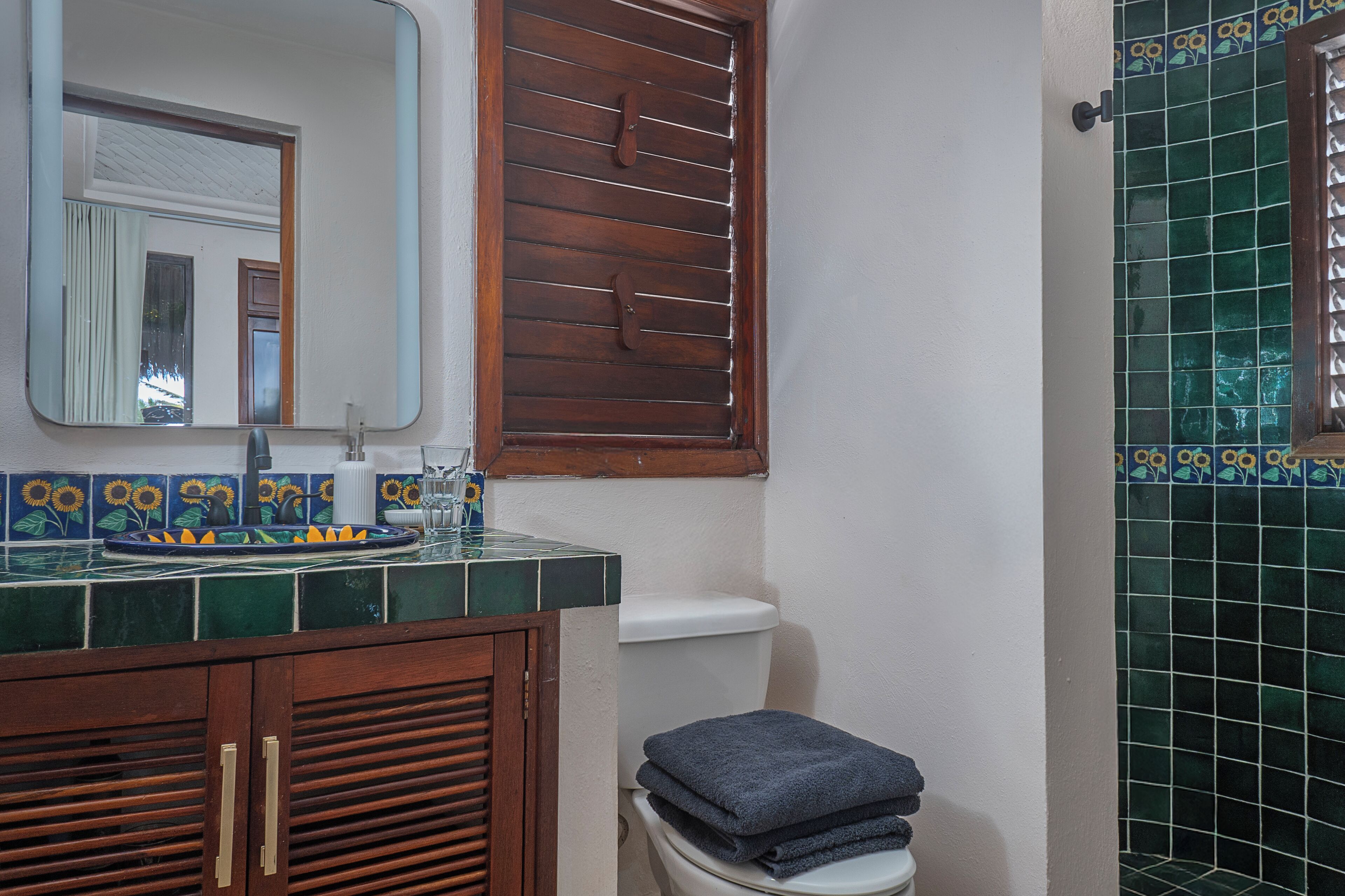 Un baño con un armario de madera, un inodoro y un lavabo con un espejo encima.