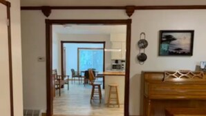 Una habitación amplia con piso de madera, un comedor con sillas y una mesa, y una cocina al fondo.