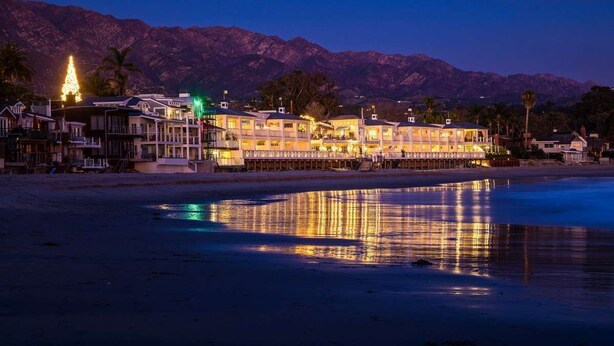 A beachfront hotel with multiple stories, a swimming pool, and a mountain backdrop. - Mid-Century Steps from Miramar Beach, Private Fenced Garden in Montecito (Montecito)