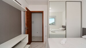 Ein modernes Hotelzimmer mit einem großen Bett, einem Kleiderschrank und einem durch eine offene Tür einsehbaren Badezimmer.
