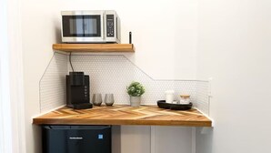 Una cocina compacta con microondas, cafetera y una pequeña planta en maceta.