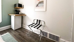 A compact kitchen with a microwave, a small refrigerator, and a metal chair. - Boutique Hotel - Suite #4 Single (Thunder Bay)
