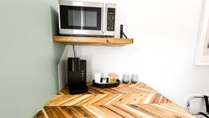 A kitchen with a microwave on a shelf, a coffee maker, and a wooden herringbone countertop. - Boutique Hotel - Suite #4 Single (Thunder Bay)