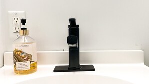 Un lavamanos con una botella de jabón para manos y un grifo negro.