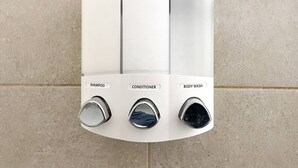 Une douche murale dotée de trois commandes distinctes, étiquetées « shampoing », « après-shampoing » et « gel douche ».