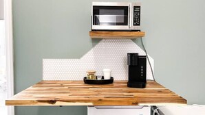 Une petite cuisine équipée d’un four à micro-ondes, d’une machine à café et d’un petit plateau avec des tasses et un pot.