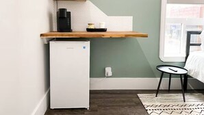 Uma kitchenette compacta com micro-ondas, cafeteira e pequena geladeira.