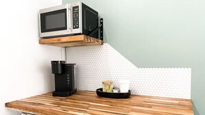 Uma cozinha compacta com micro-ondas, cafeteira e uma pia pequena.
