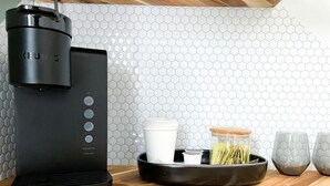 A black Keurig coffee maker on a wooden countertop with a hexagonal tile backsplash.