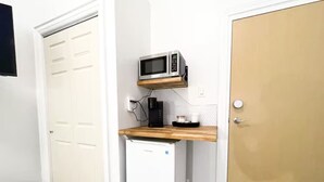 A compact kitchen with a microwave, a small refrigerator, and a wooden countertop.