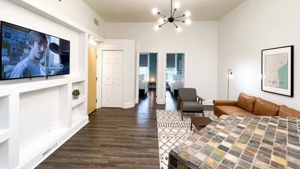 A modern living room with a flat-screen TV, a patterned rug, and a brown leather sofa. - Boutique Hotel - #10 Two Double (Thunder Bay)