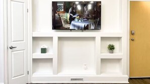 A room with a mounted television on the wall, a door, and a shelf with a small plant. - Boutique Hotel - #10 Two Double (Thunder Bay)