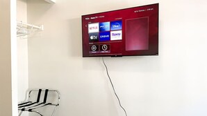 Ein an der Wand befestigter Flachbildfernseher zeigt eine Streaming-Dienstanwendung mit Optionen wie Netflix, Apple TV und Roku.
