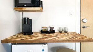 Eine kompakte Küchenzeile mit Mikrowelle, Kaffeemaschine und kleinem Kühlschrank.