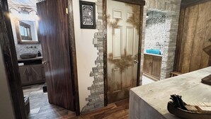 Une salle de bain rustique avec un mur en pierre, une porte en bois et un grand miroir.