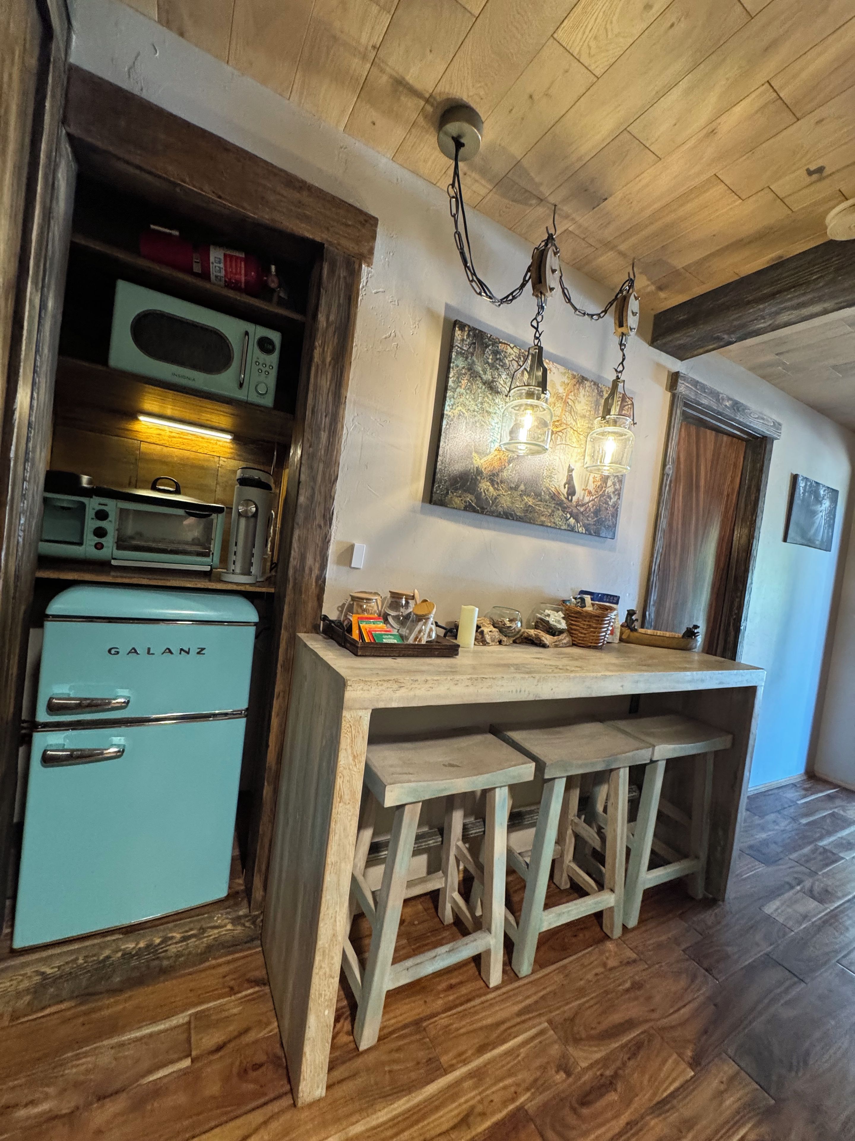 Una cocina con un refrigerador Galanz de estilo vintage, un microondas y una barra de madera con taburetes.
