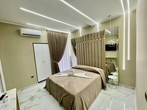 A modern hotel room with a bed, a vanity with a mirror, and a marble floor. - AT THE NAPLES TRACK VIP ROOM (Napoli)