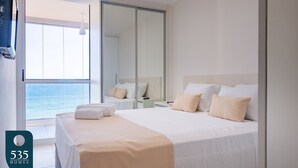 Ein Hotelzimmer mit einem großen Bett, einer Schiebetür zum Balkon und Meerblick.