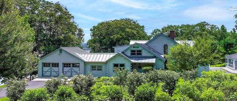 Ein hellblaues Haus mit Garage, umgeben von üppiger Vegetation und bunten Blumen.