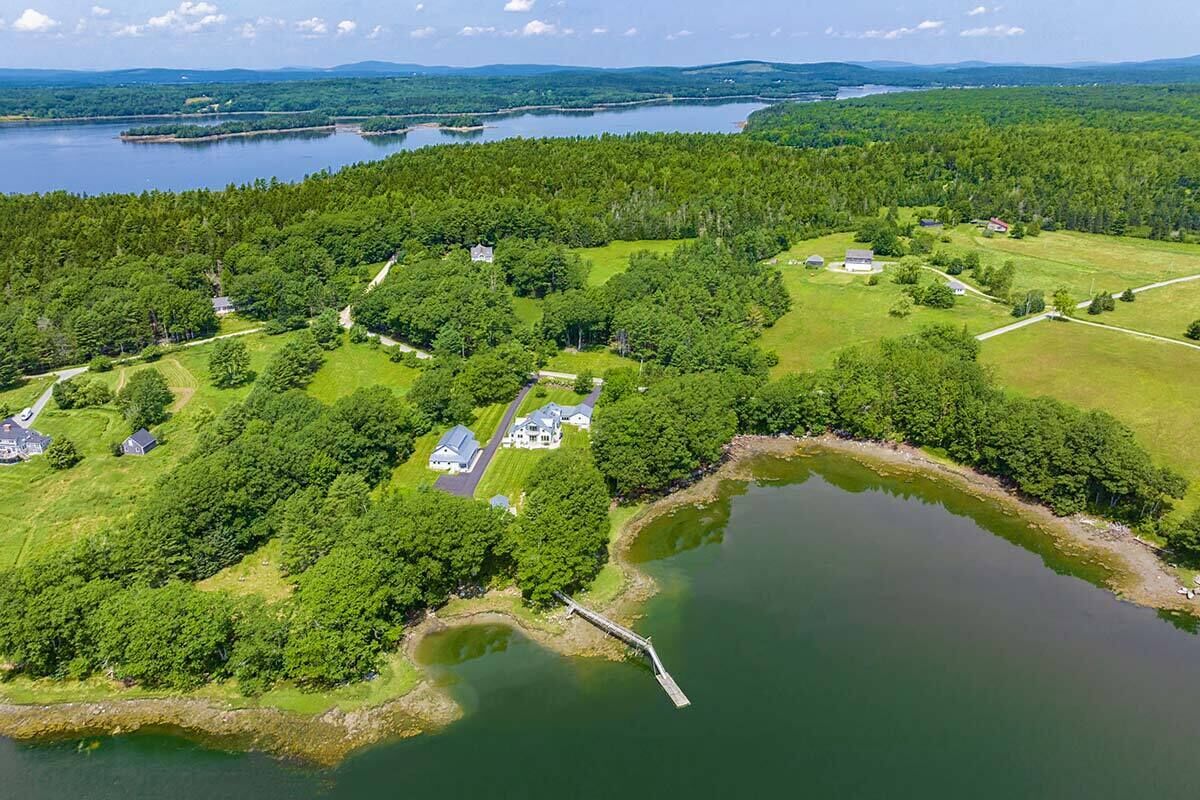 An aerial view of a large estate with multiple houses, a dock, and a lake.