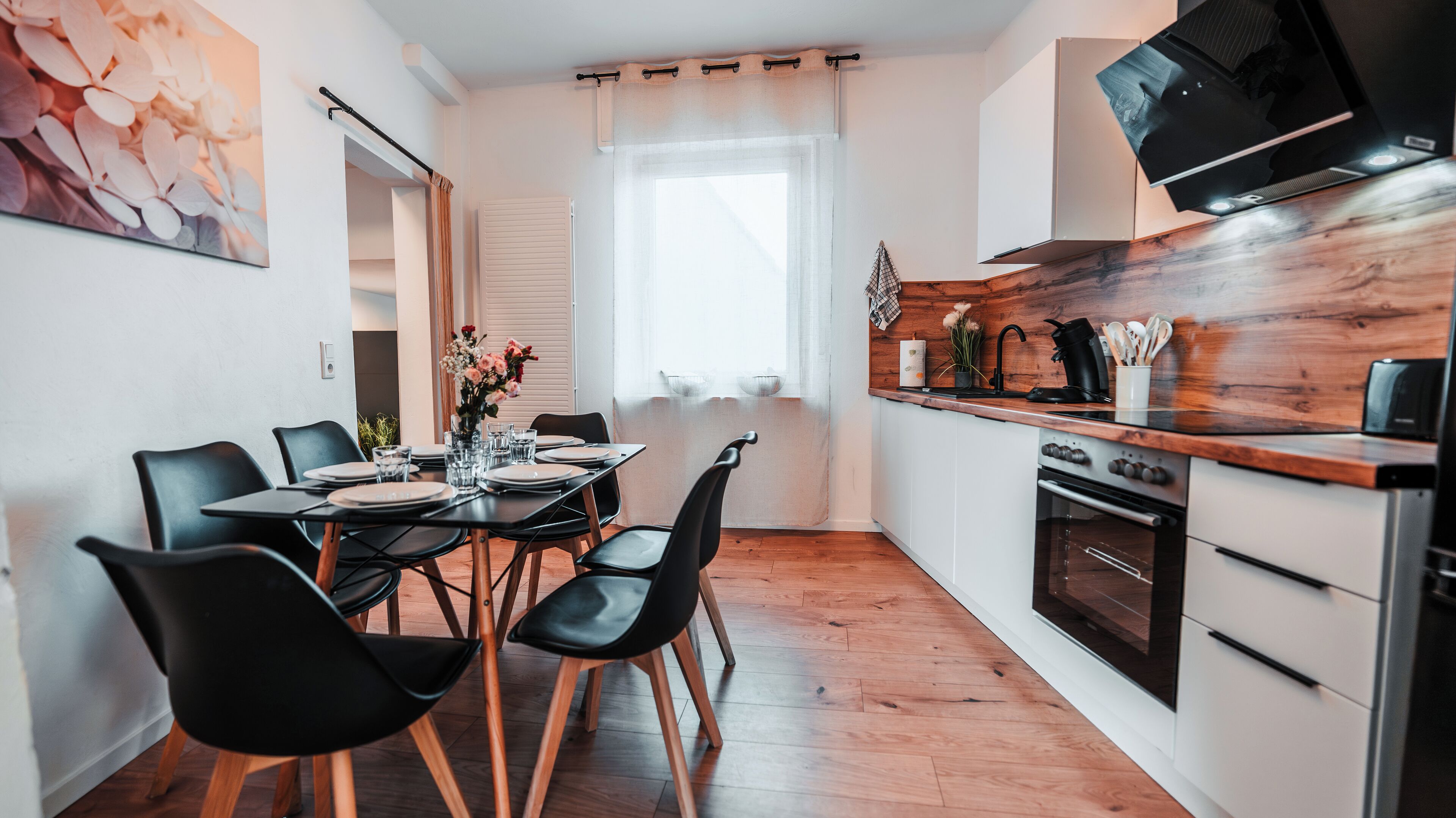 A modern kitchen with a wooden countertop, a built-in oven, and a dining area with a table set for four.