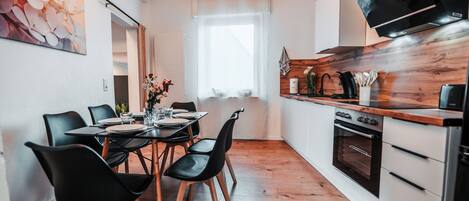A modern kitchen with a wooden countertop, a built-in oven, and a dining area with a table set for four.