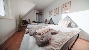 A bedroom with a large bed, a potted plant, and two framed artworks on the wall. - FlexHome Stylish vacation apartment (Lippstadt)