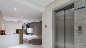 A modern reception area with a reception desk, a plant, and a wall-mounted sign. - 50" Smart TV | 500 meters from UFSC #TRINA03D (Florianópolis)