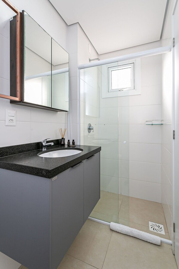 Une salle de bain moderne avec un grand miroir, un lavabo et une douche à parois de verre.