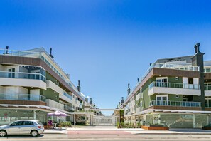 A modern multi-story hotel with a glass facade, outdoor seating, and a clear sky.