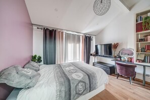 Relax in this serene bedroom with a large bed, flat-screen TV, and comfortable workspace.