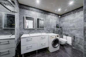 Enjoy a sleek bathroom with a wall-mounted mirror, washing machine, and spacious sink.