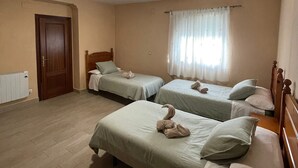 A room with two single beds, a wooden door, a radiator, and a window with curtains. - Casa La Peña (Pet friendly) 1 min drive from the beach! (La Redonela)