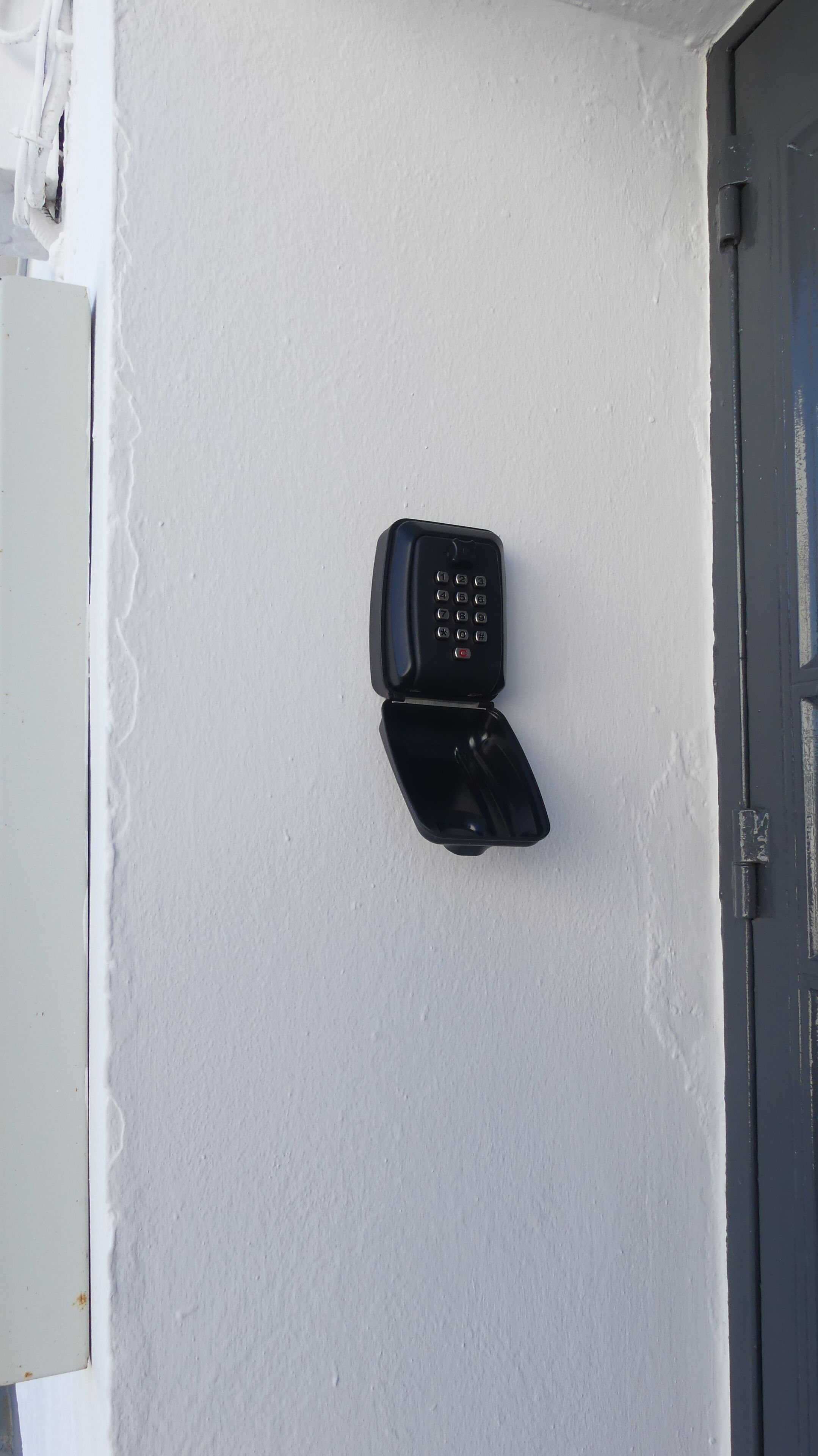 A black intercom mounted on a white wall.