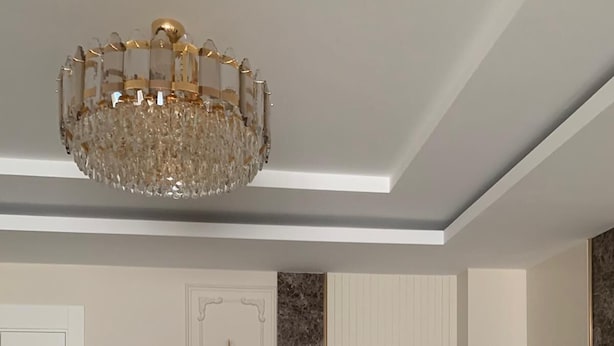 A modern living room with a white sofa set, a chandelier, and a marble accent wall. - YİLDİRAY YİLMAZ GENEL TRADİNG FZ-LLC (Ras Al Khaimah)