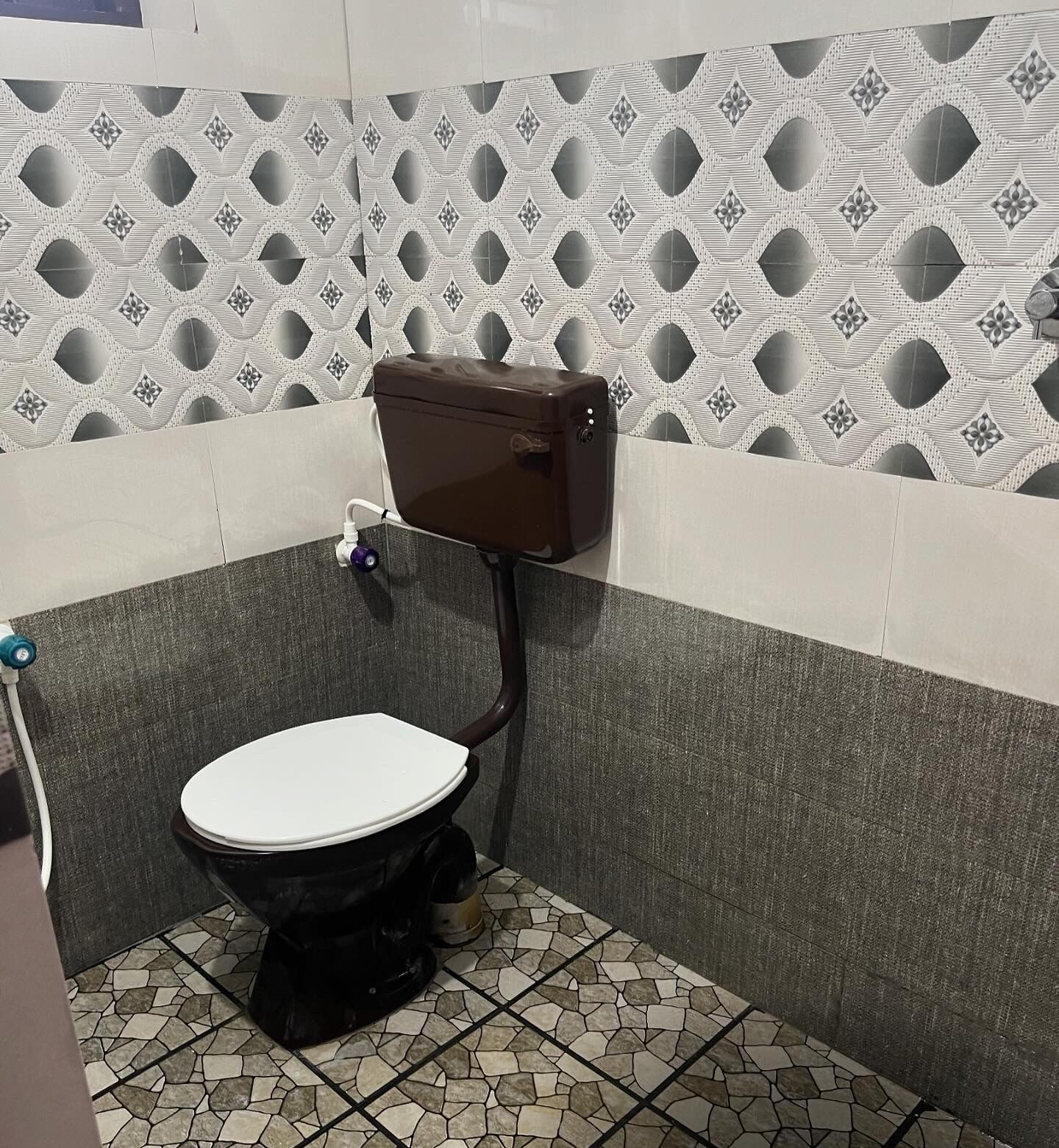 Un bagno piccolo con il water, un serbatoio a muro e pavimento piastrellato.
