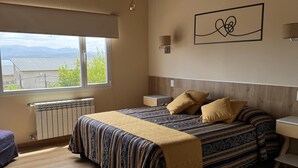 Ein Schlafzimmer mit einem großen Bett, einem Nachttisch, einem Fenster mit Bergblick und einer Decke mit freiliegenden Balken.