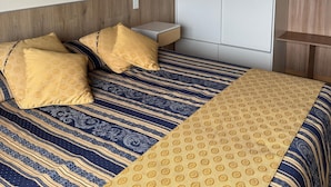 Ein Schlafzimmer mit Bett, Kleiderschrank, Nachttisch und einer Wandlampe.
