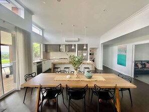 A modern kitchen with a central island, dining area with chairs, and a view of the outdoors.