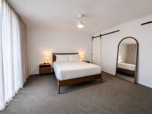 A hotel room with a bed, bedside tables, a ceiling fan, a large mirror, and a sliding door. - The Loop—Rural Retreat with Pool & Valley Views (Western Australia)