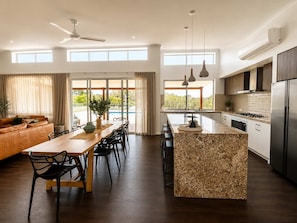 Cozinha moderna com ilha central, eletrodomésticos embutidos e grandes janelas.