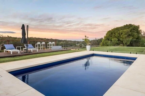 A swimming pool with lounge chairs and a view of the landscape.
