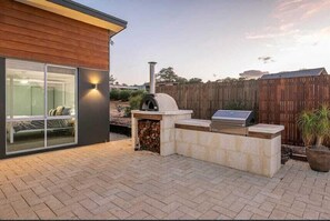 A modern house with a patio, a wood-burning stove, and a barbecue grill.