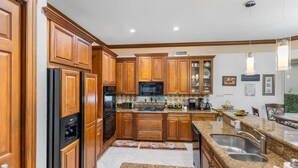 A kitchen with wooden cabinets, a microwave, a stove, and a sink. - Spacious 5-bedroom house in charming Wellington with WiFi, AC (Wellington)