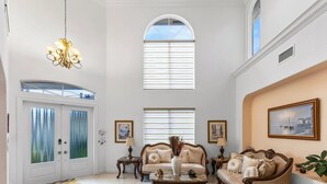 A spacious living room with a high ceiling, a chandelier, a sofa set, a coffee table, and a painting on the wall. - Spacious 5-bedroom house in charming Wellington with WiFi, AC (Wellington)
